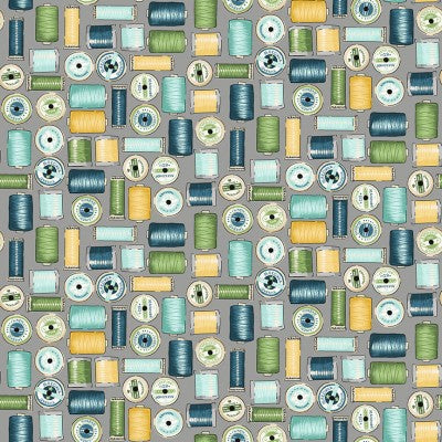 photo showing the design on fabric, cotton reels in blue green and yellow on a grey background